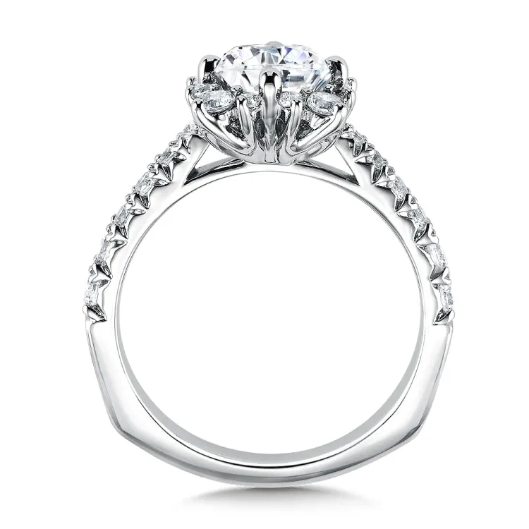 Varied sizes of prong-set diamonds surround the dazzling center stone. Pinched diamond shoulders add maximum sparkle.